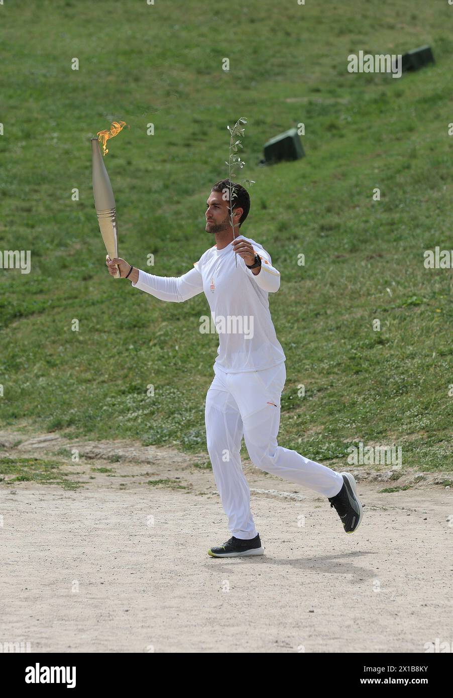 Antigua Olimpia, Grecia. 16 de abril de 2024. El primer portador de la antorcha, el campeón olímpico griego de remo Stefanos Ntouskos, corre con la antorcha olímpica durante la ceremonia de iluminación de llama olímpica para los Juegos Olímpicos de Verano de París 2024 en la Antigua Olimpia, Grecia, el 16 de abril de 2024. Crédito: Zhao Dingzhe/Xinhua/Alamy Live News Foto de stock