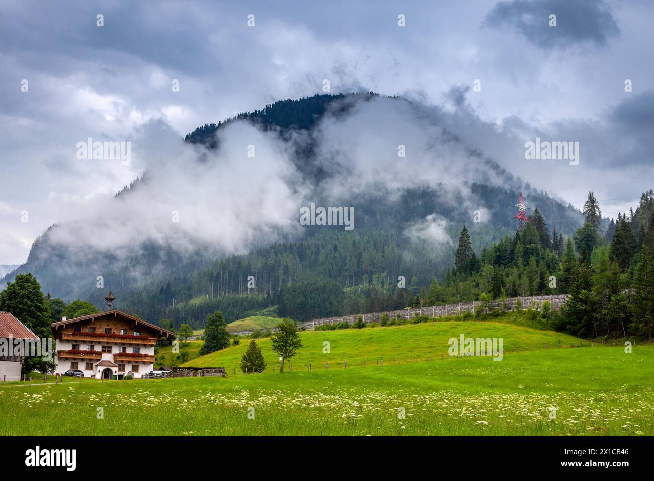 Prado alpino y chalet en Flachau, Austria, con montañas brumosas. Foto de stock
