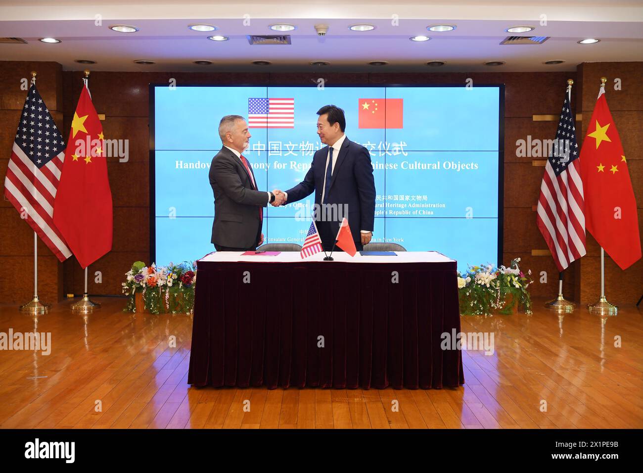 Nueva York, Estados Unidos. 17 de abril de 2024. El Viceministro de Cultura y Turismo de China y jefe de la Administración Nacional del Patrimonio Cultural, Li Qun (R), da la mano a Matthew Bogdanos, jefe de la Unidad de Tráfico de Antigüedades de la Fiscalía del Distrito de Manhattan, en una ceremonia de entrega de objetos culturales chinos devueltos en el Consulado General de China en Nueva York, Estados Unidos, el 17 de abril de 2024. El lado estadounidense devolvió 38 piezas de objetos culturales chinos al lado chino el miércoles. Crédito: Li Rui/Xinhua/Alamy Live News Foto de stock