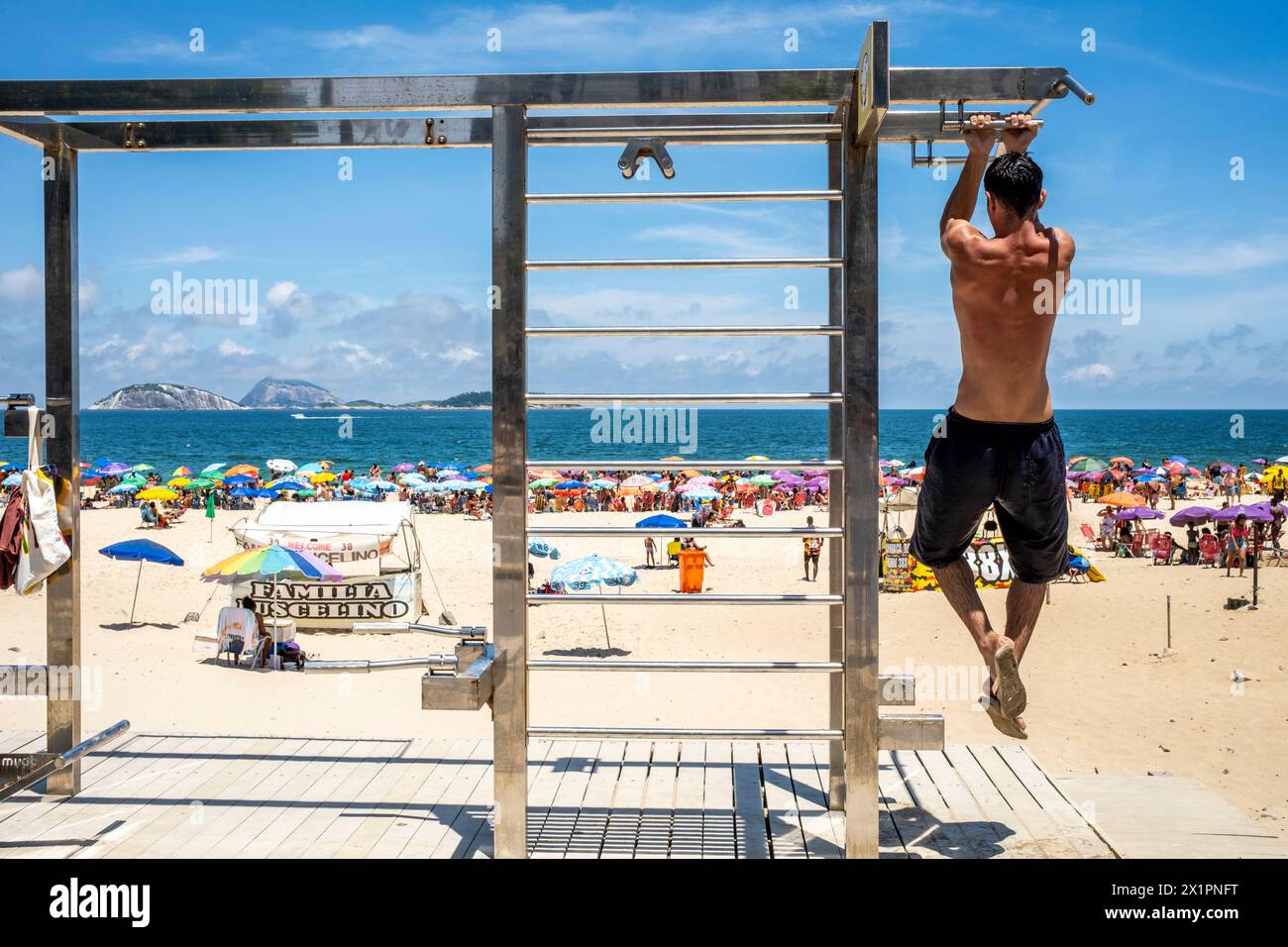 Un joven haciendo pull Ups en una estación de ejercicios en la playa de Ipanema, Ipanema, Río de Janeiro, Brasil. Foto de stock