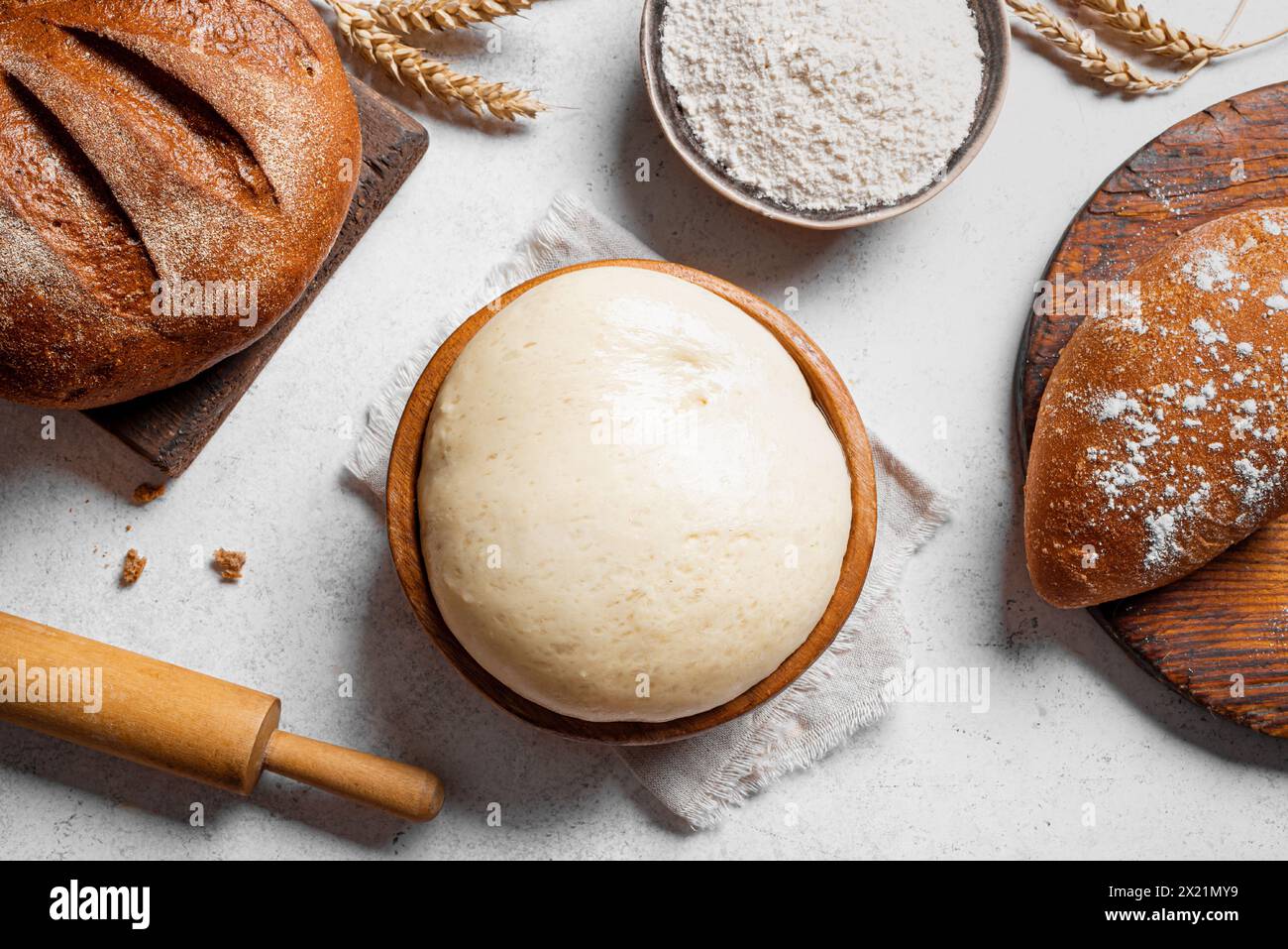 Tazón de masa de levadura fresca con harina, rodillo y pan de masa madre fresca sobre fondo blanco. Concepto de horneado, pastelería y amasado. Foto de stock