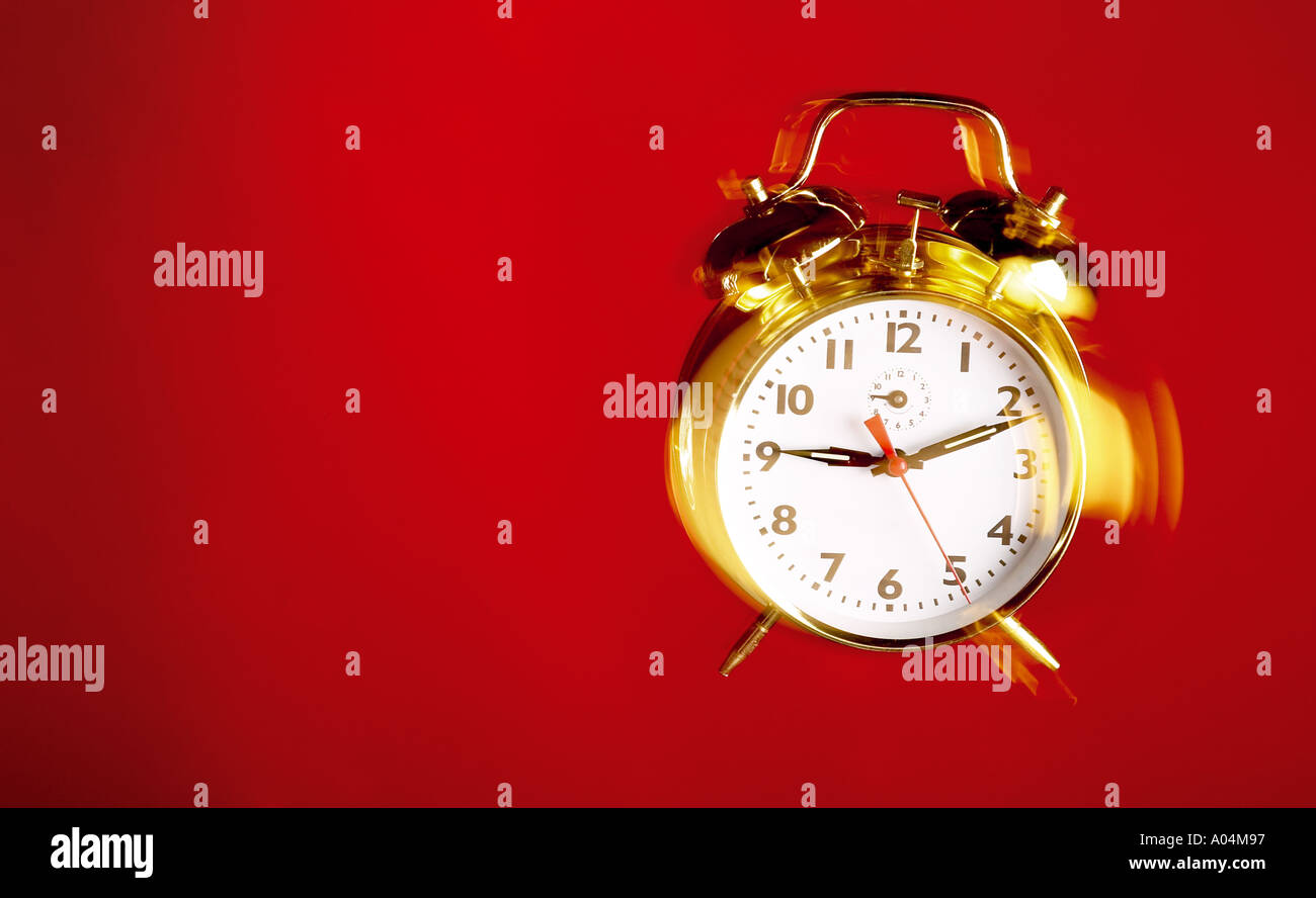 Paisaje shot de oro reloj alarma sonando en un fondo rojo. Foto de stock