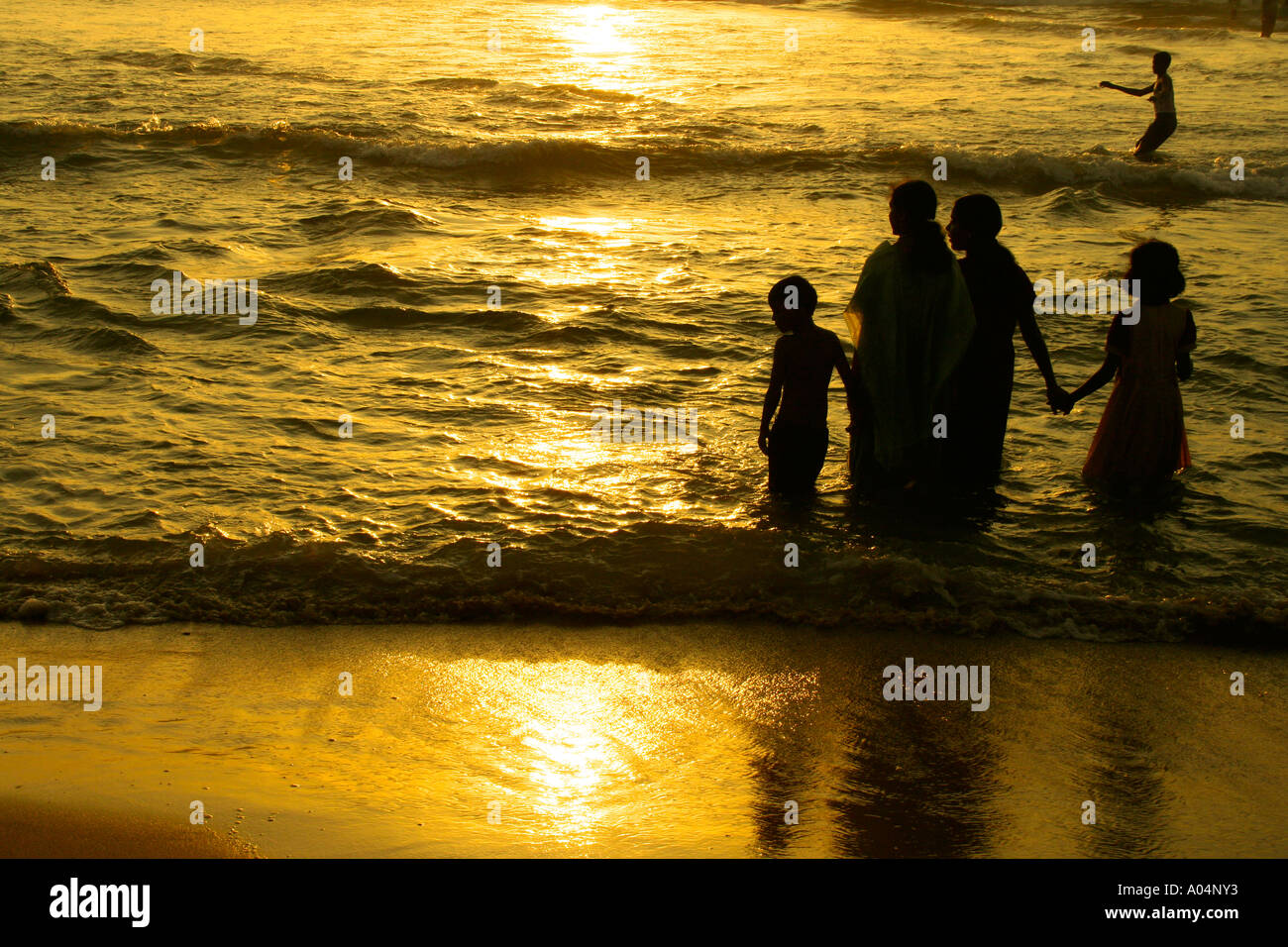 Una familia disfrutando de la puesta de sol en la playa Kovalam, en Kerala Foto de stock