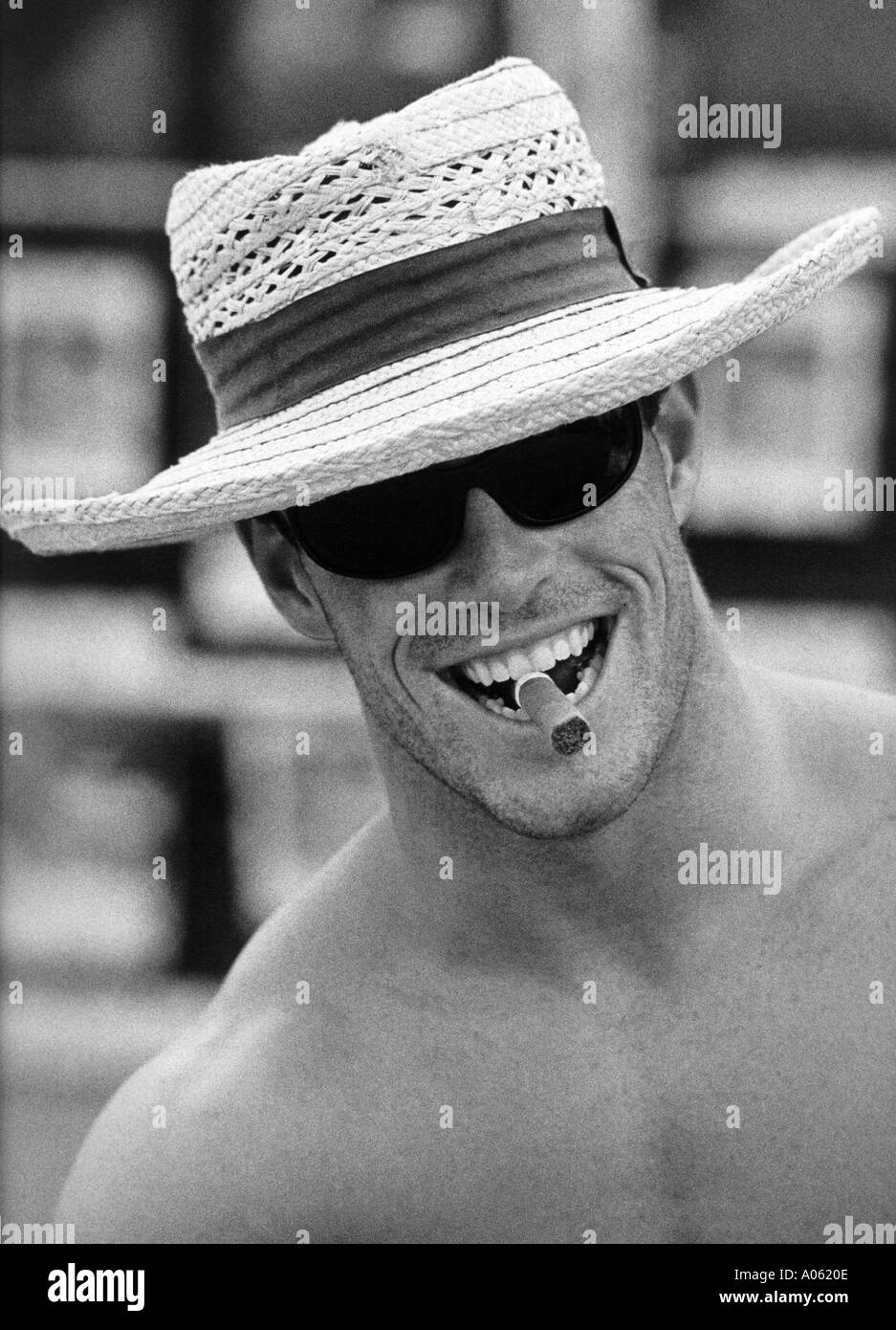 Hombre sonriente en el sombrero de paja y gafas de sol cigarro fumar Foto de stock