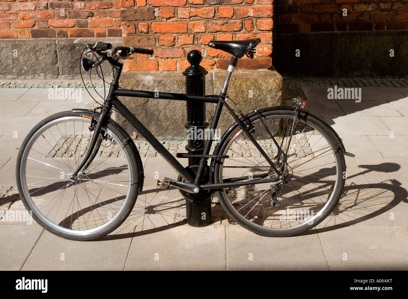 Antigua bicicleta negra aparcamiento cerca de calle negro polo con pared de  ladrillo rojo en el fondo Fotografía de stock - Alamy