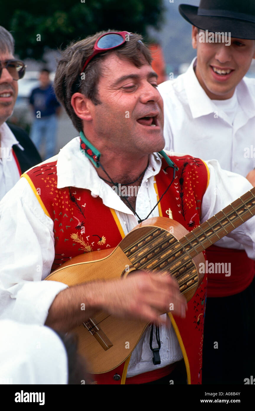 Un músico vestía un chaleco rojo bordado sobre una camisa blanca cantando  una canción como él acompaña a sí mismo en su guitarra durante la Fiesta  Romera en Santa Cruz Fotografía de