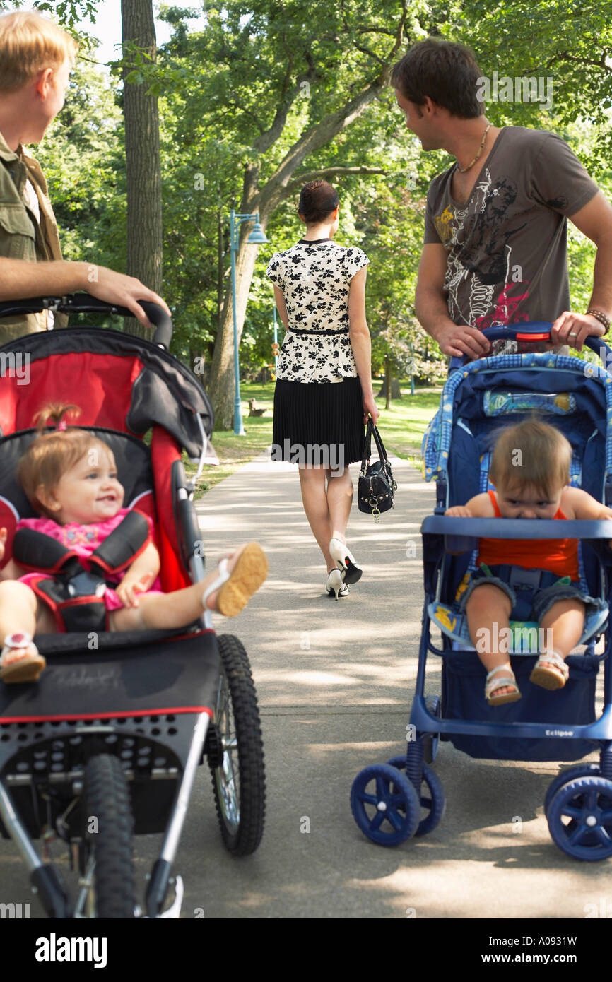 Los hombres con bebés en cochecitos mirando a la mujer Caminando Foto de stock