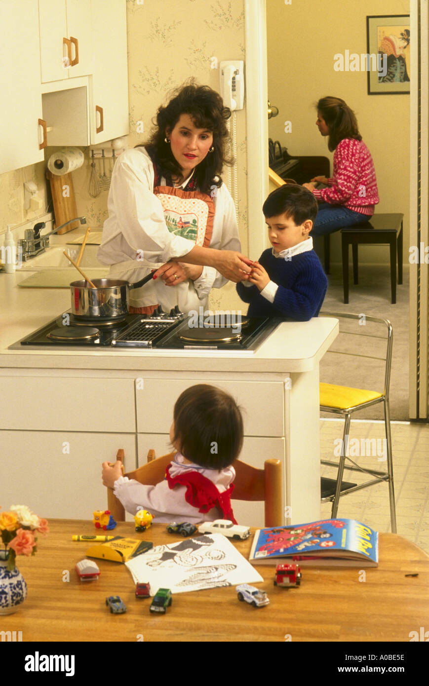 Mamá en la cocina cocinar con ella chiIdren jugando y ayudando Foto de stock