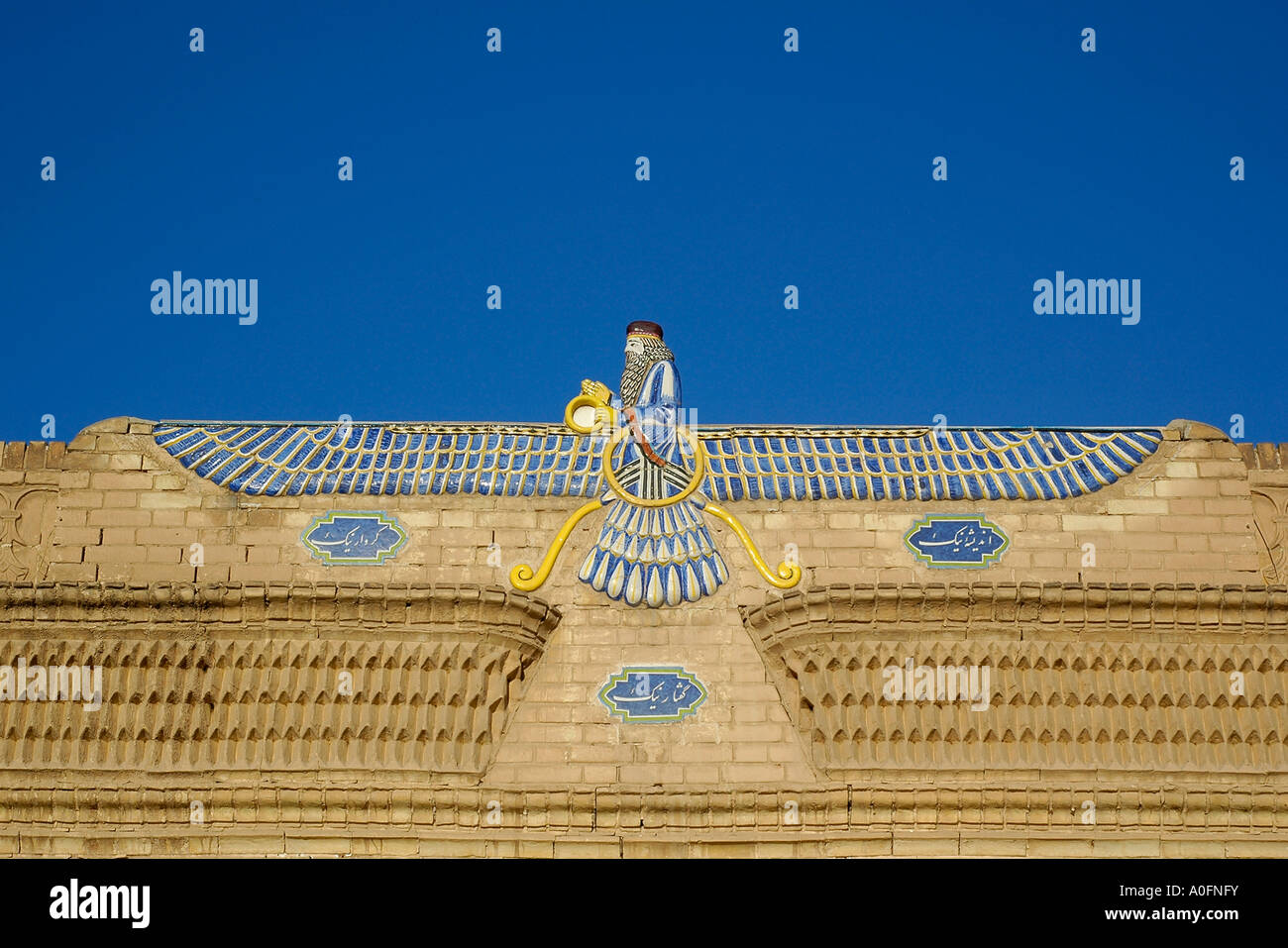 Una foto horizontal del símbolo alado de la religion Zoroastriana, encima de la entrada del templo de fuego de Yazd, Irán. Foto de stock