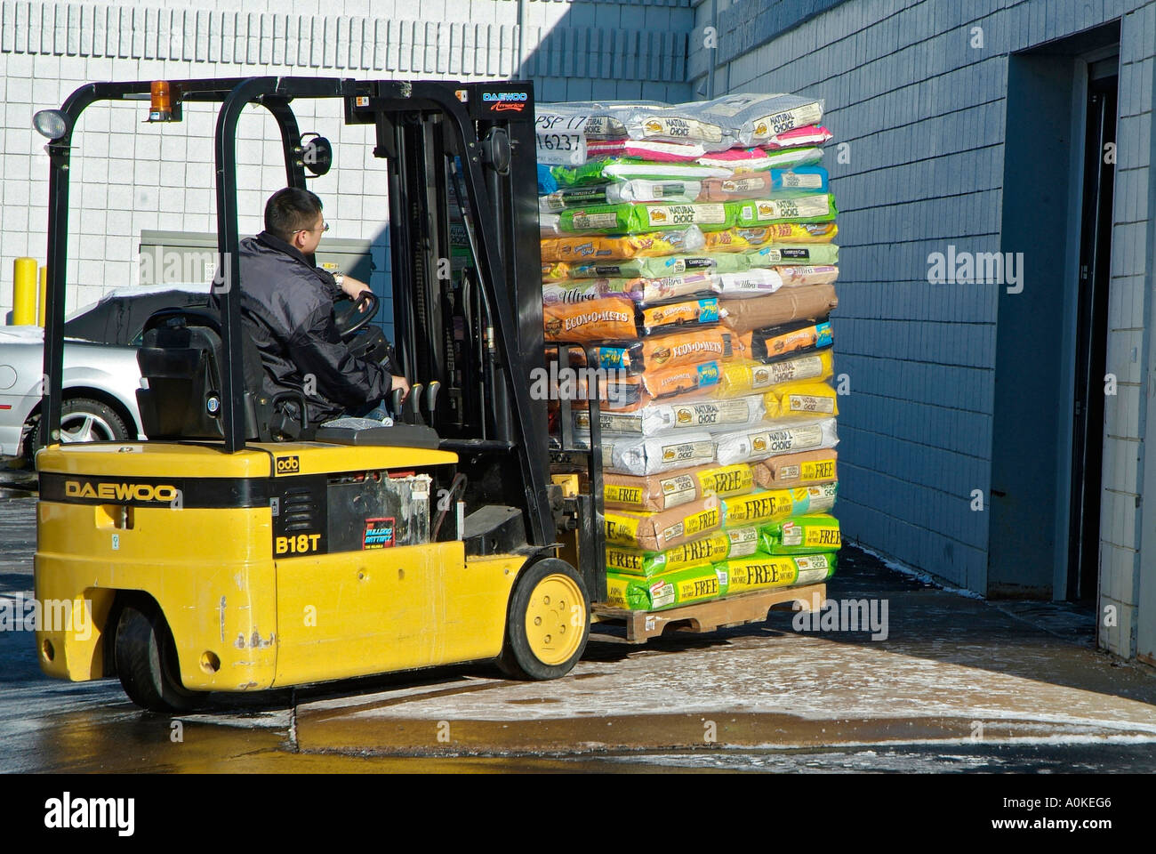 Operador de montacargas mueve una pesada carga de productos desde un camión a un punto de venta Operador de montacargas mueve una pesada carga de productos desde un camión a un punto de venta