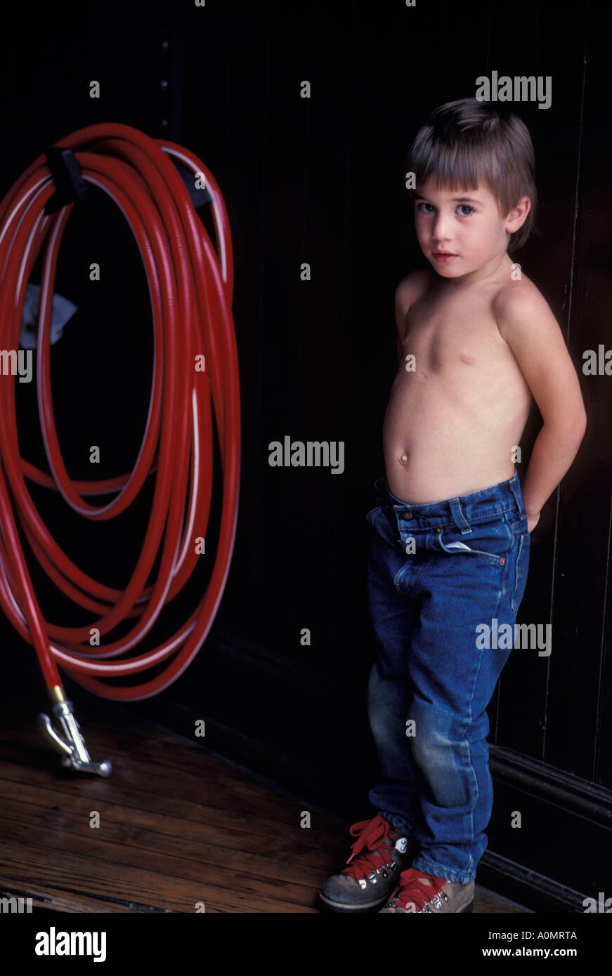 1 Un joven muchacho descamisado blue jeans botas rojas manguera de agua  Fotografía de stock - Alamy