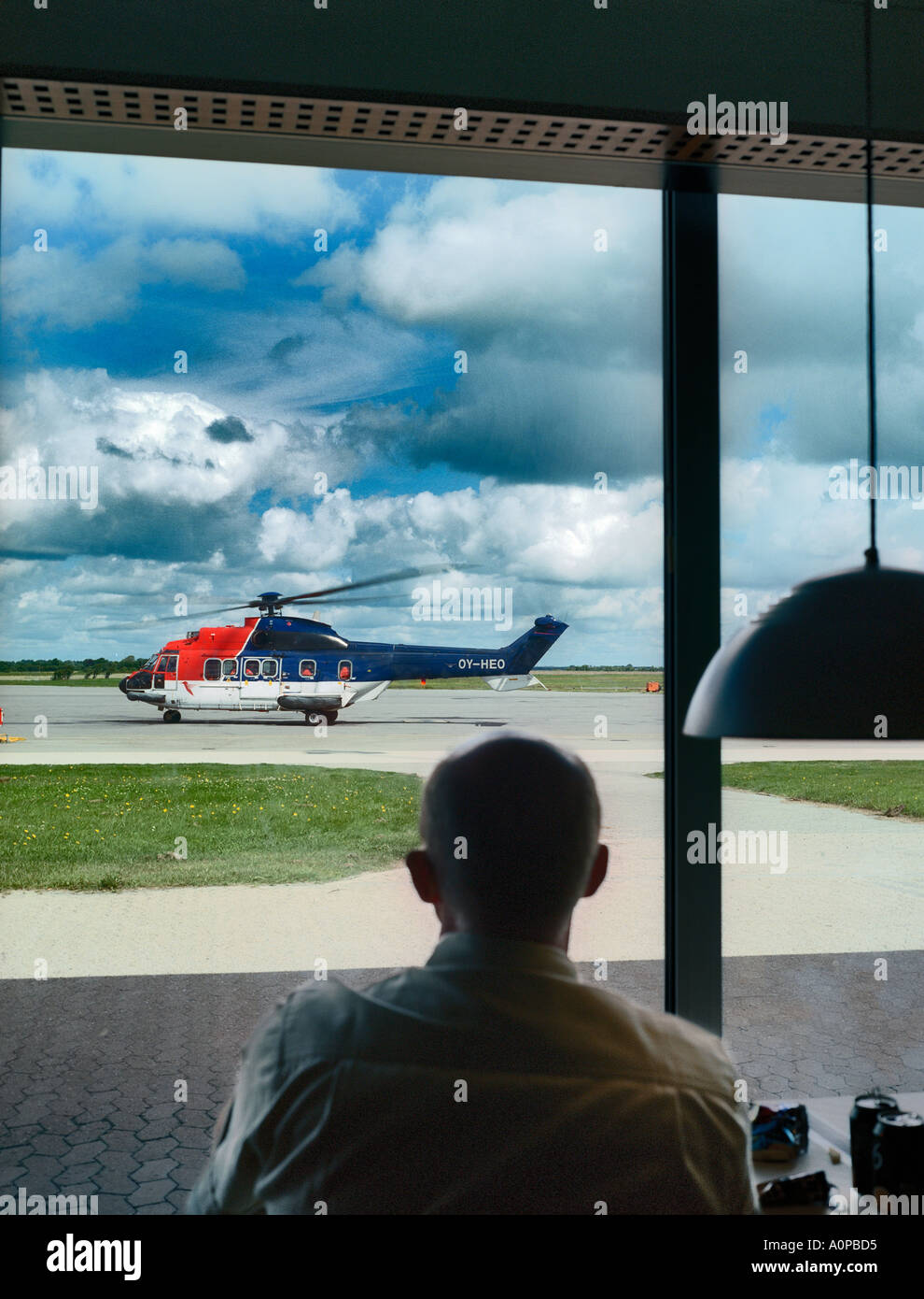 Hombre mirando un helicóptero listo para tomar de trabajadores con Maersk para una de las plataformas petroleras en el Mar del Norte el aeropuerto de Esbjerg Dinamarca Foto de stock