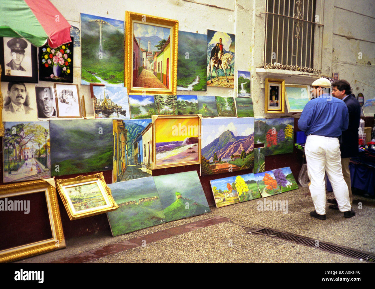 Artista callejero hombre mostrando sus pinturas en el centro de la ciudad y hablar con el concesionario San Cristóbal Venezuela Sur América Latina Foto de stock