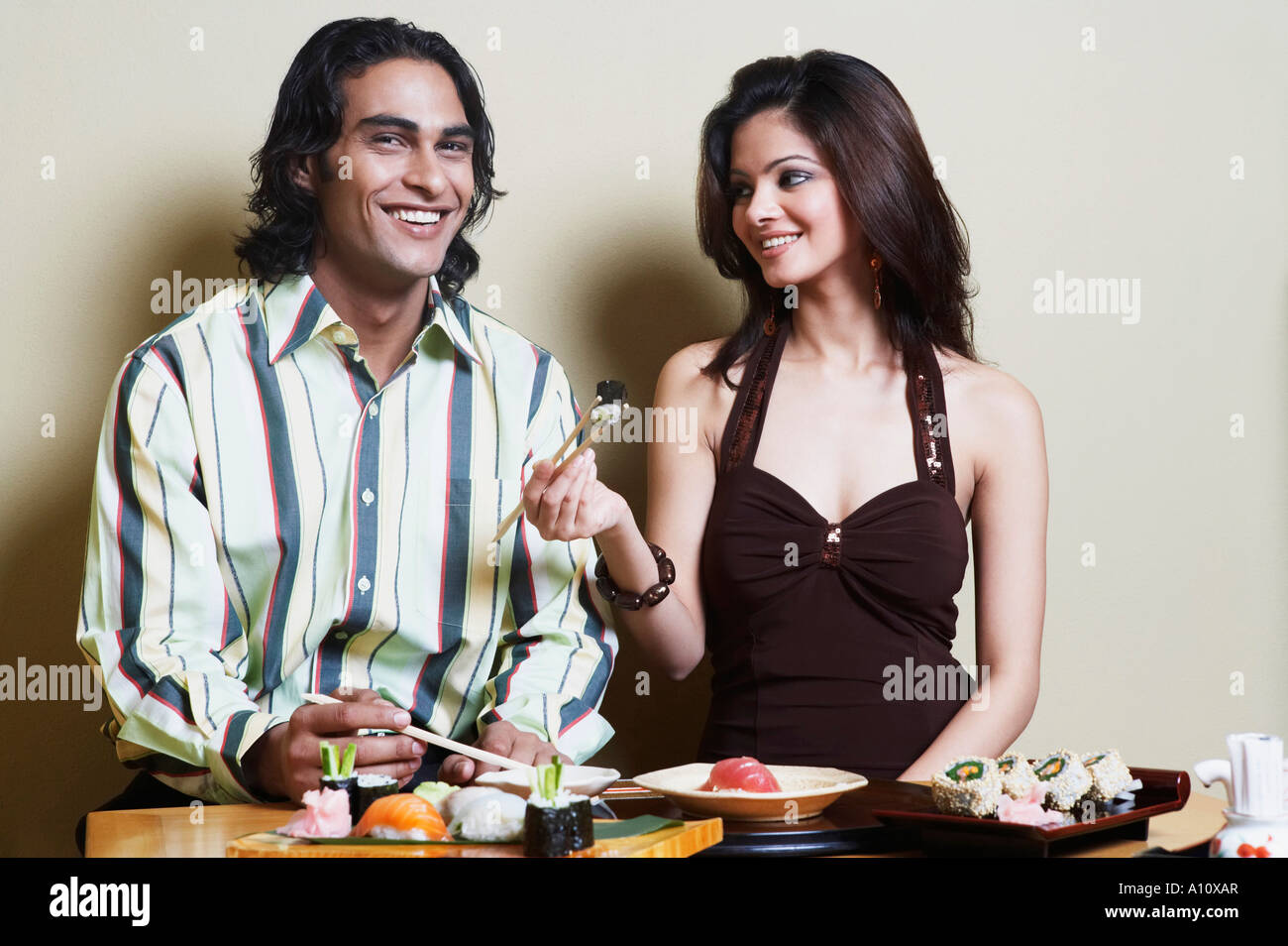 Retrato de un hombre joven con una mujer joven sentada en una mesa de comedor y sonriente Foto de stock