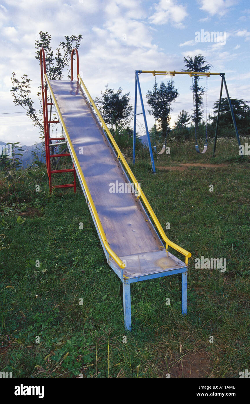 Parque infantil con columpio para bebés y deslice cerca de casas Fotografía  de stock - Alamy