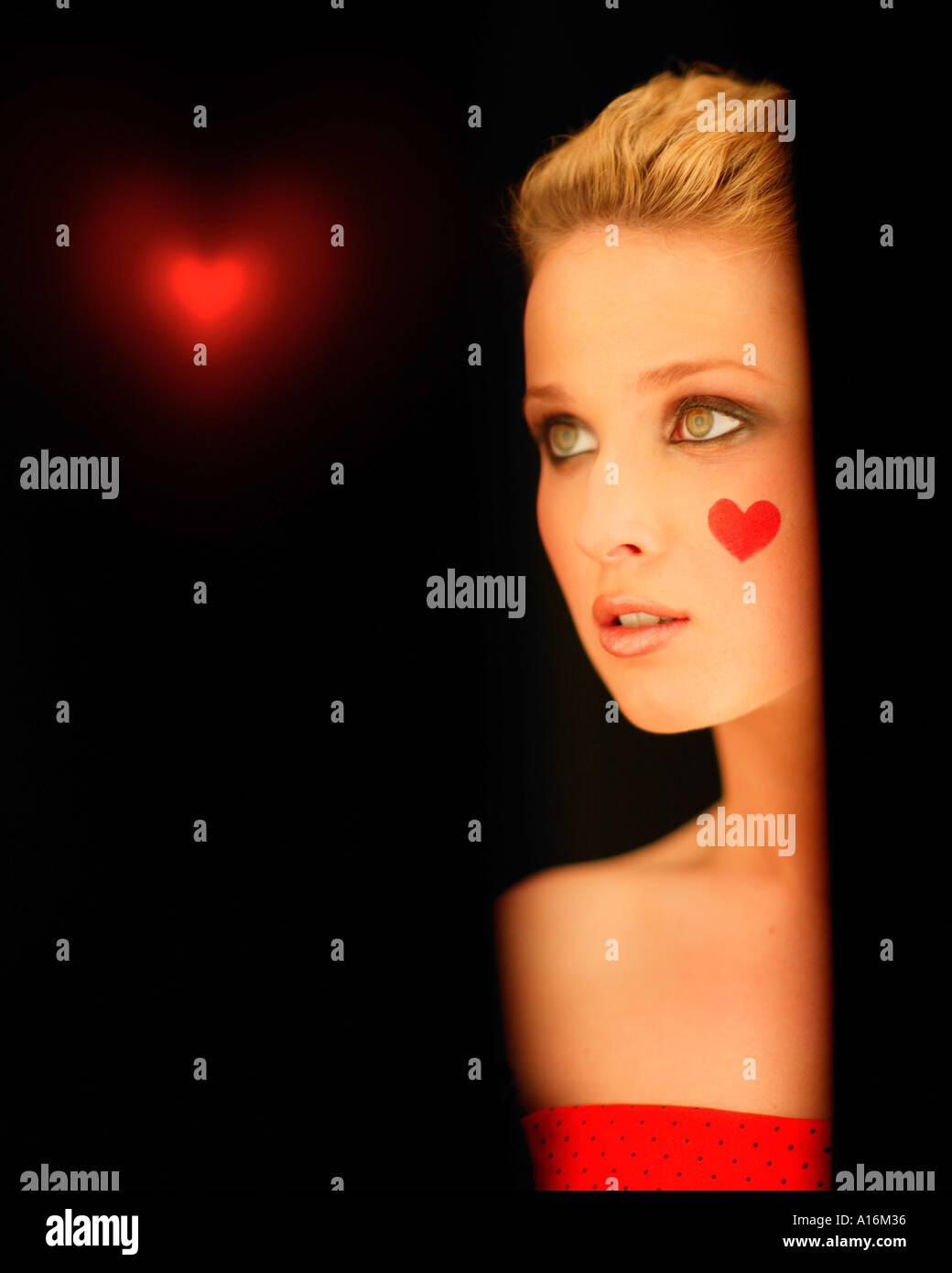 Retrato de una joven 18, 19, 20, 21, 20-24, 24-29, 30-34, de edad con corazón rojo pintado en su mejilla Foto de stock