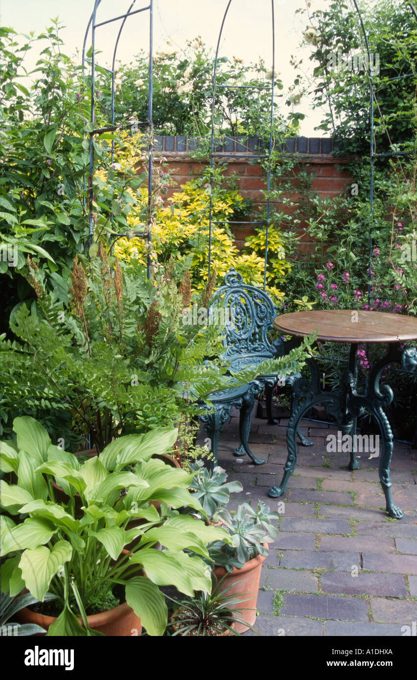 Muebles de jardín de hierro fundido verde en el pequeño patio Fotografía de  stock - Alamy