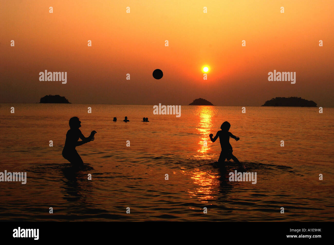 Jugando a la pelota en el océano al atardecer, Tailandia Ko Chang Foto de stock