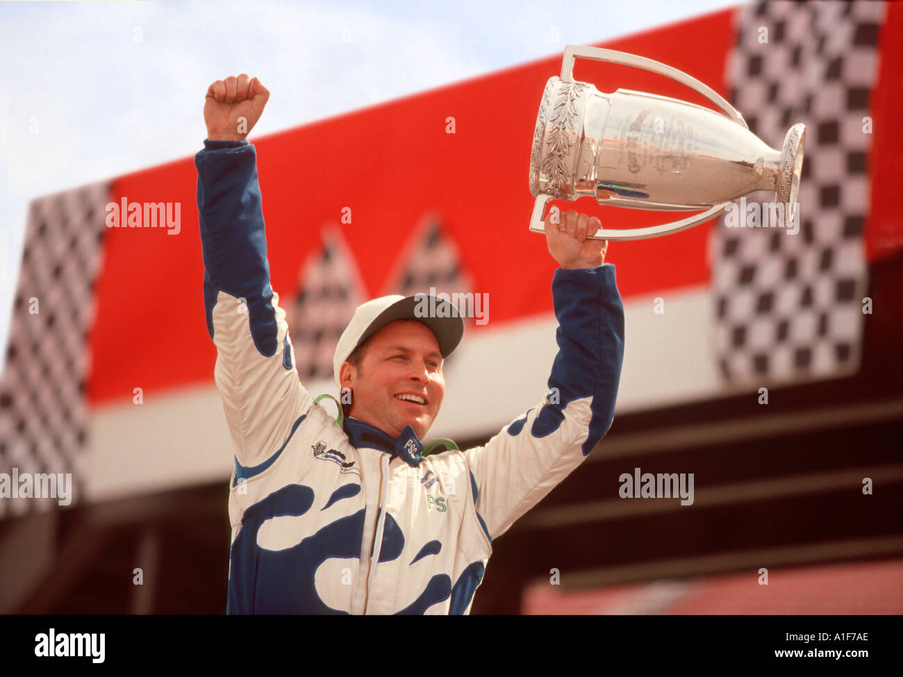 Conductor de autos de carrera ganadora sosteniendo el trofeo del campeonato en el Círculo de ganadores después de la carrera Foto de stock