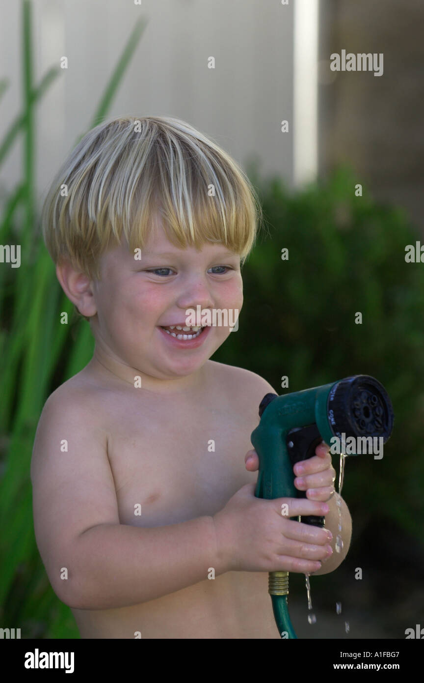 Feliz desnudo infante regar con una manguera de jardín Fotografía de stock  - Alamy