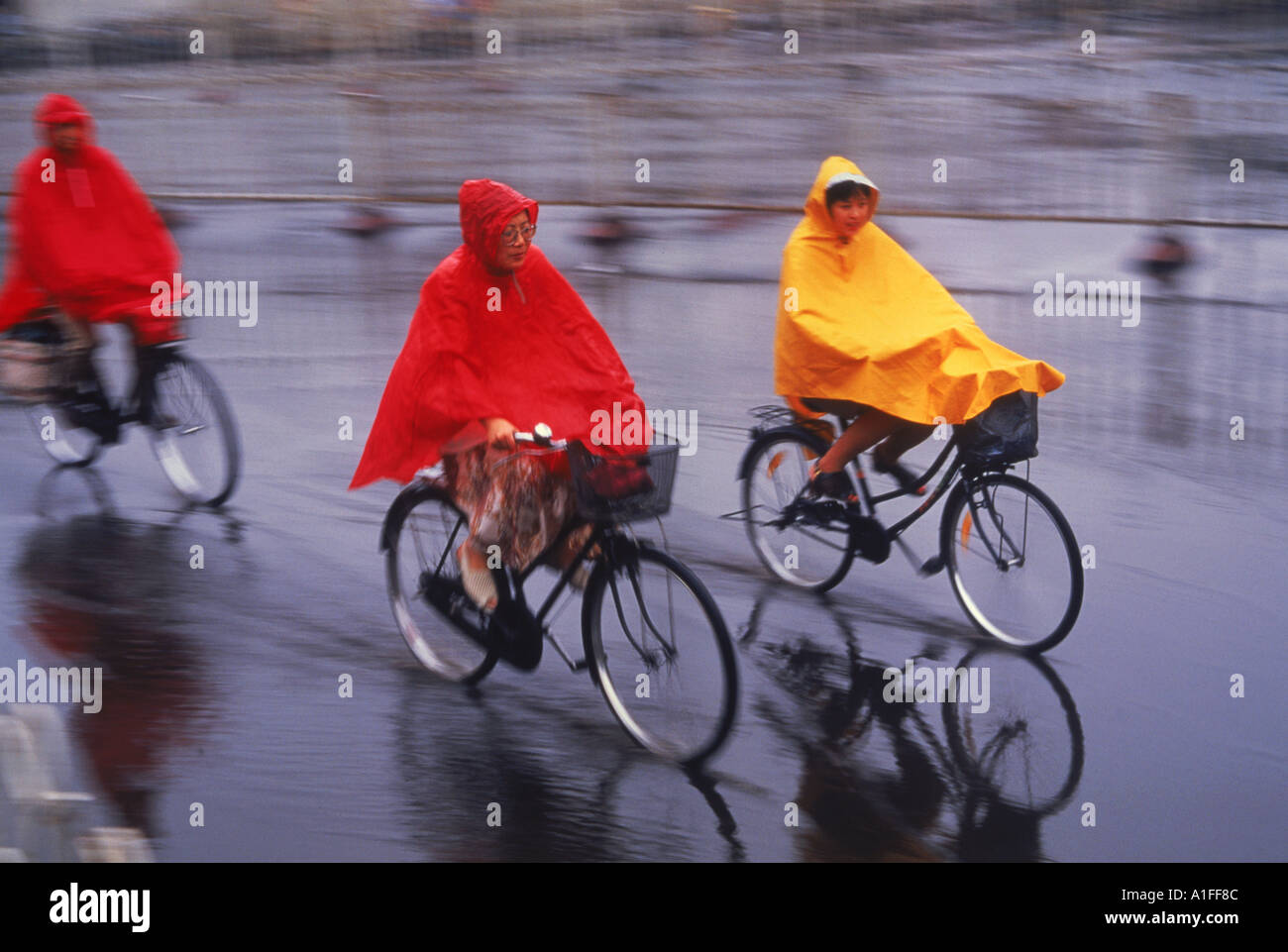 La mujer en capas impermeables en bicicleta en la lluvia en Beijing China P  Van Riel Fotografía de stock - Alamy