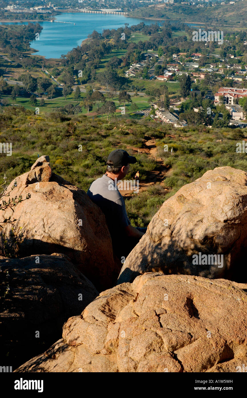 Hombre sentado sobre una roca a lo largo de senderos con vistas a San Diego. Foto de stock