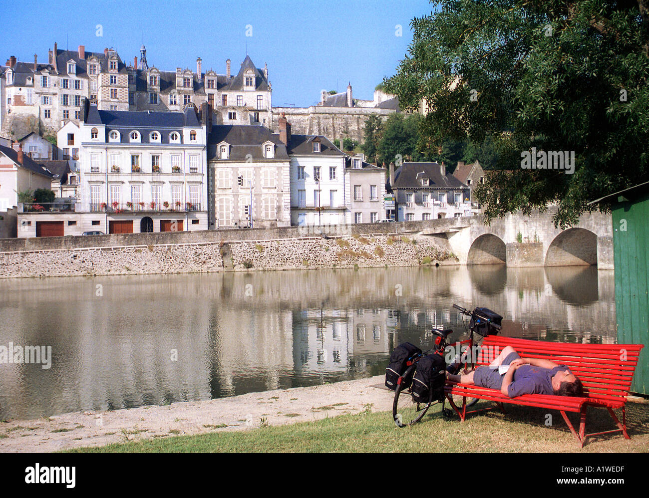 Ciclista descansando en un banco por el banco de la Cher en St Aignan Foto de stock