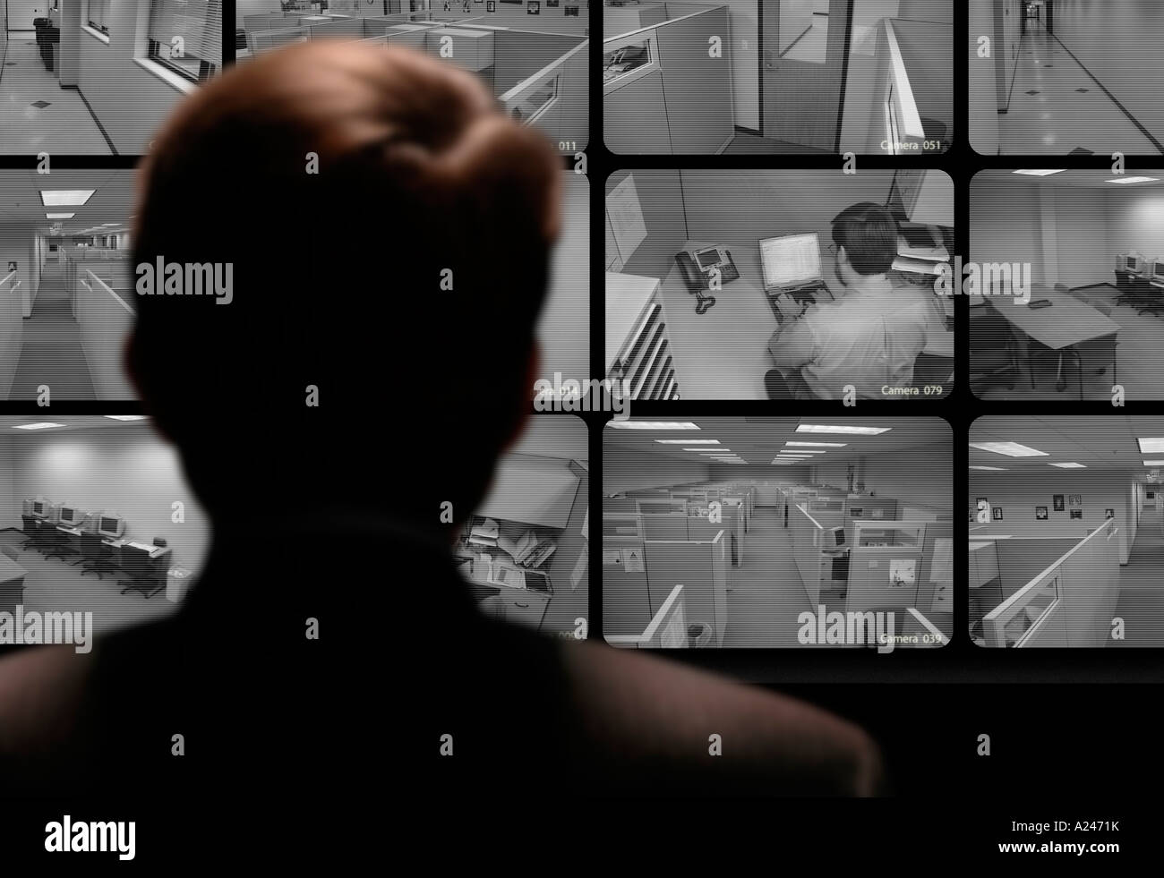 Hombre mirando el trabajo de un empleado a través de un monitor de vídeo de circuito cerrado Foto de stock