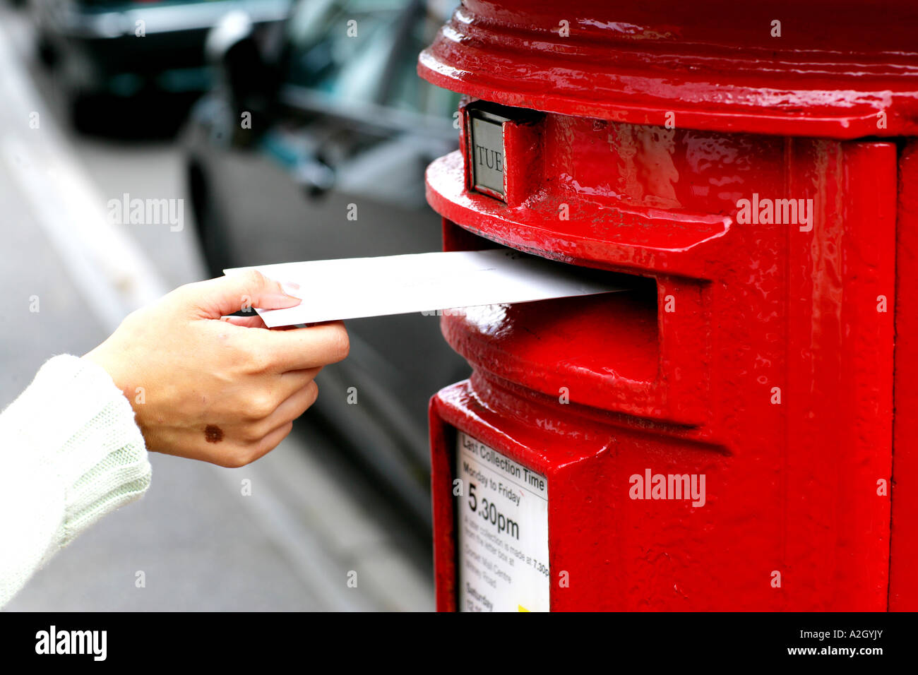 Persona que plantea una carta en un rojo Post Office Box de contabilización en el lado de la calle Foto de stock