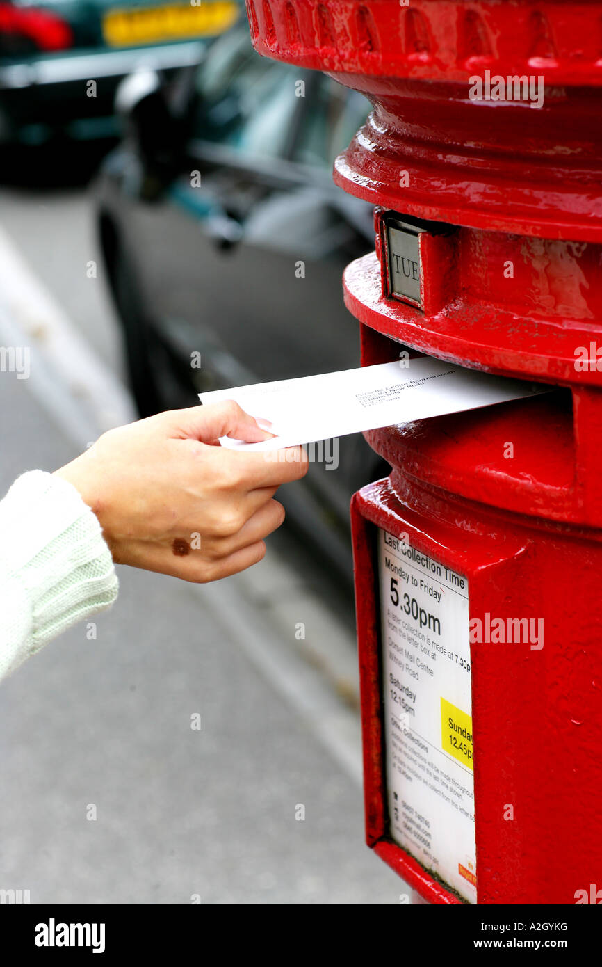 Persona que plantea una carta en un rojo Post Office Box de contabilización en el lado de la calle Foto de stock