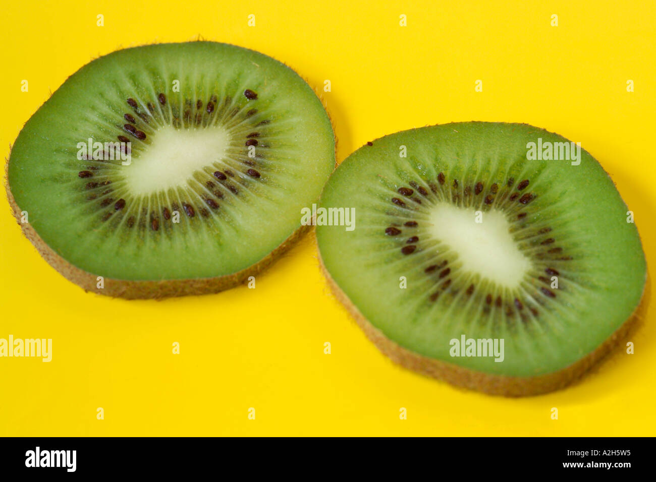 Dos rodajas de kiwi en el fondo amarillo Foto de stock