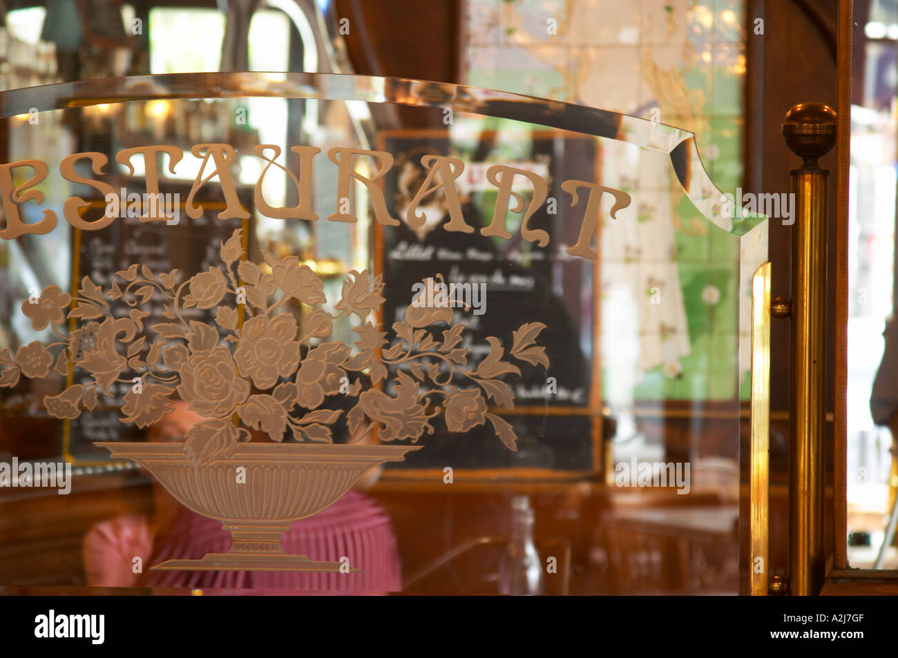 Detalle de una mampara de vidrio particionar facetas y grabado grabado  Restaurante texto y un ramo de flores. En el fondo los espejos y el menú  del Bistrot du Peintre es un