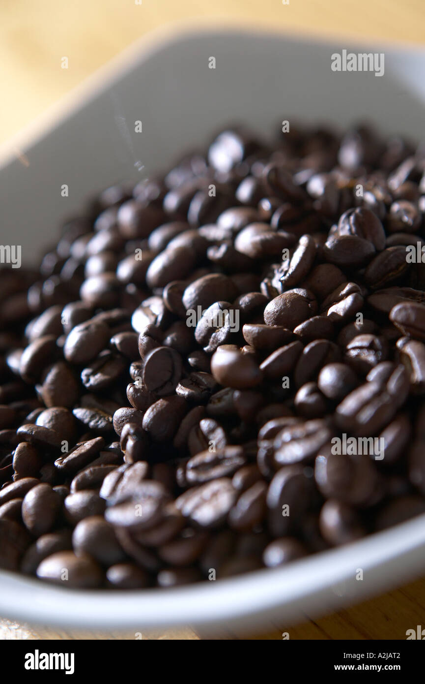 Los granos de café en un plato esperan molienda. Foto de stock