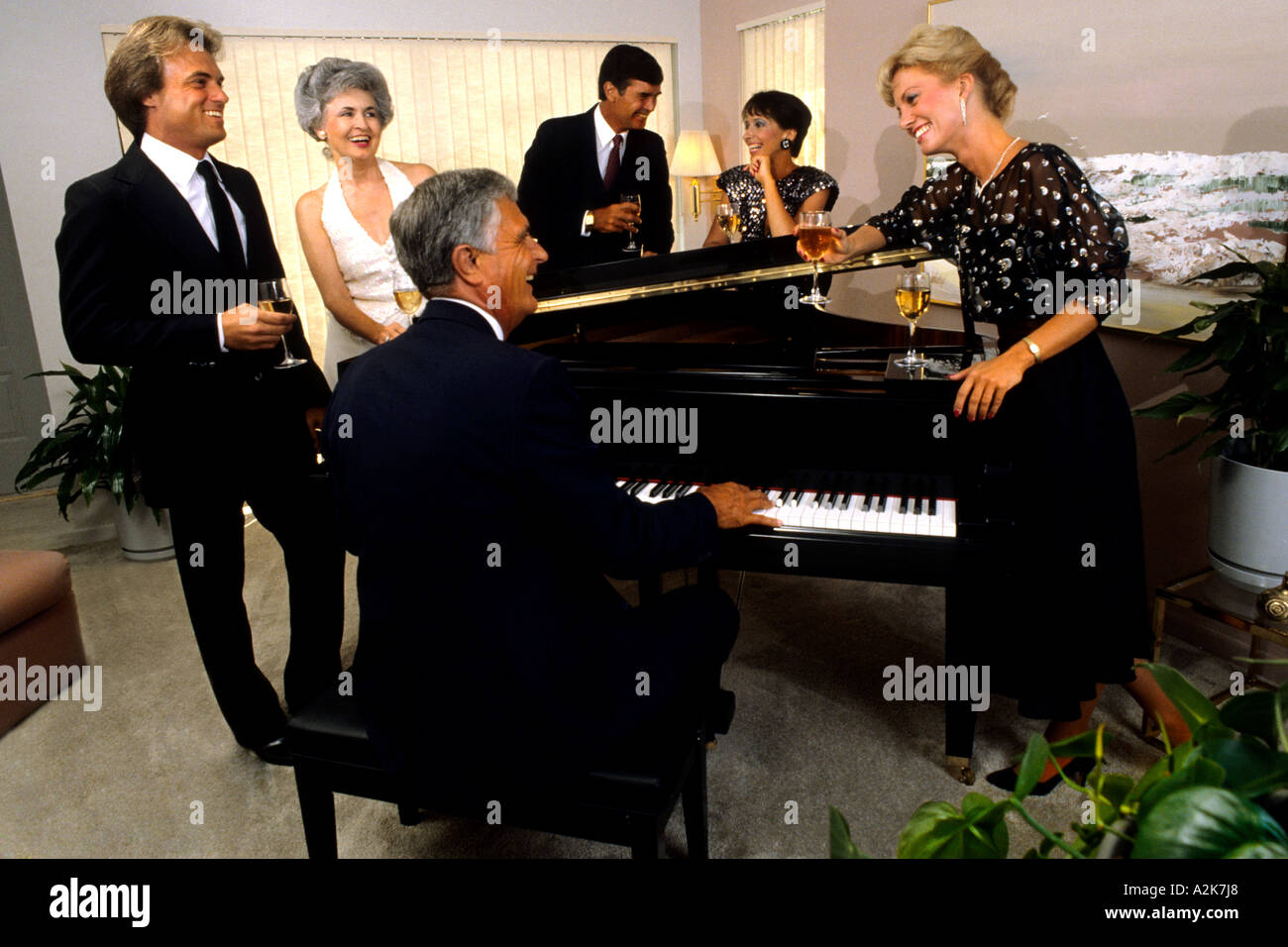 Elegantemente vestido de parejas de cena tocando el piano y tomando bebidas  en la buena vida Fotografía de stock - Alamy