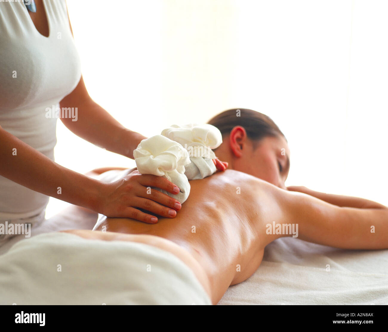Vista trasera de joven mujer desnuda recibiendo masajes con piedras de  calentamiento de terapista de masaje Fotografía de stock - Alamy