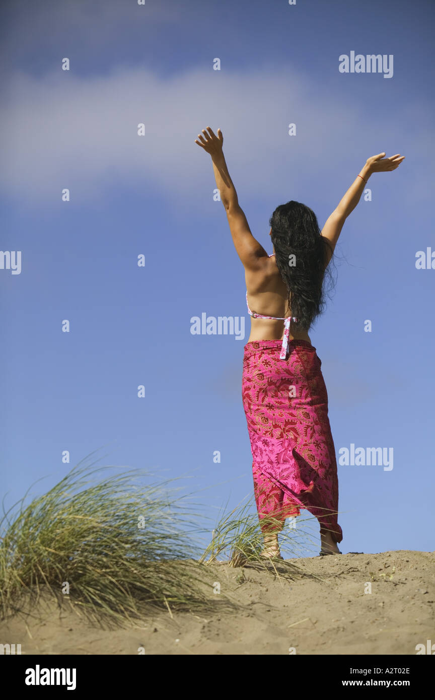 Mujer con los brazos estirados en una playa Foto de stock