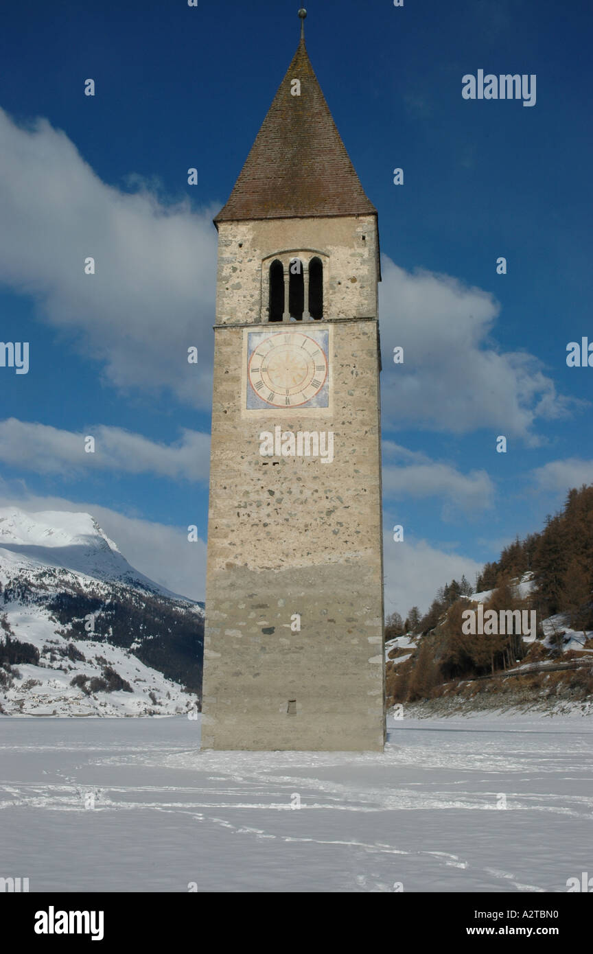 Torre de la iglesia de Graun ahogado en congelados damed hidroeléctrico Lago Resia Reschensee Tirol del Sur Alto Adige Italia Foto de stock