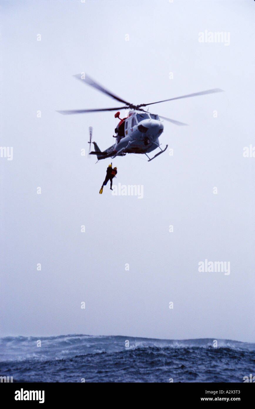 Aire de rescate en el mar helicóptero winching persona para seguridad del tormentoso océano. Foto de stock