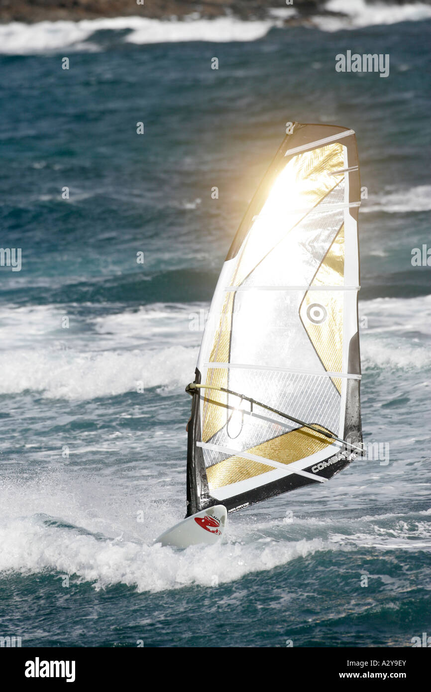 Sol brilla un dorado y negro vela windsurf en el mar frente a la playa de El Medano Tenerife Islas Canarias Foto de stock