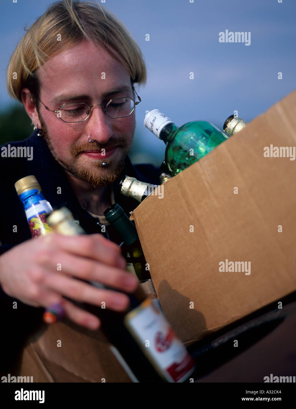 Persona en sus veinte años de reciclaje de botellas de cerveza en la unidad de reciclaje al norte de Gales, Reino Unido Foto de stock