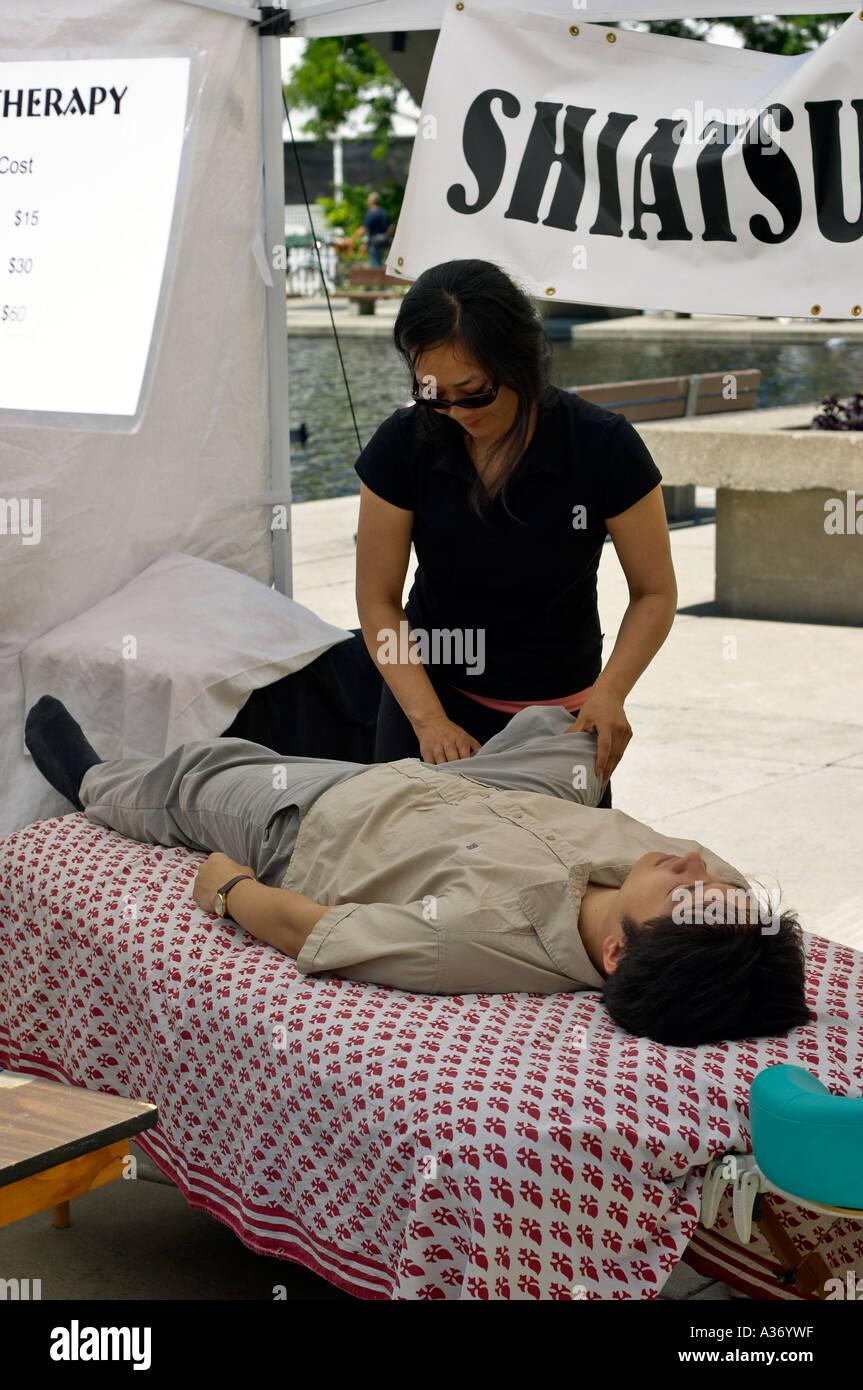 Terapeuta de Shiatsu con un paciente. Stand de demostraci n