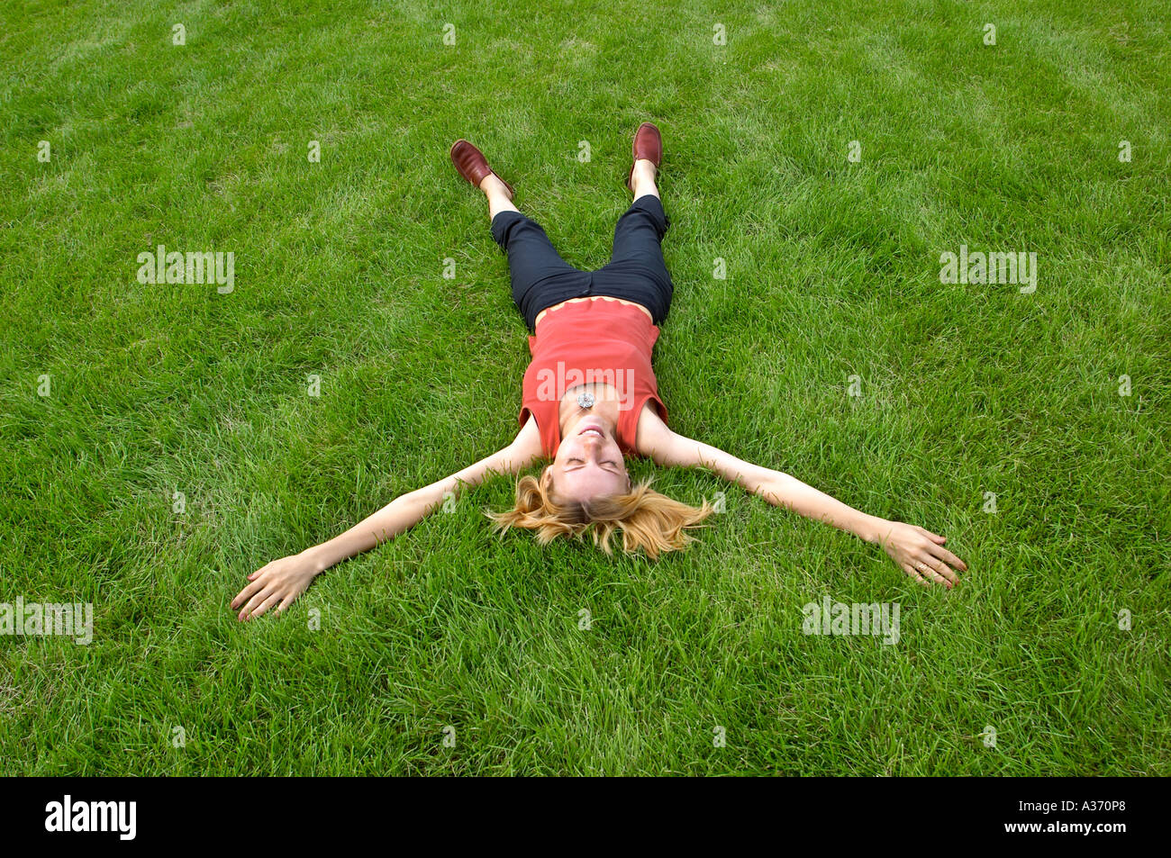 Mujer descansando en la hierba con brazos y piernas abiertas. Foto de stock