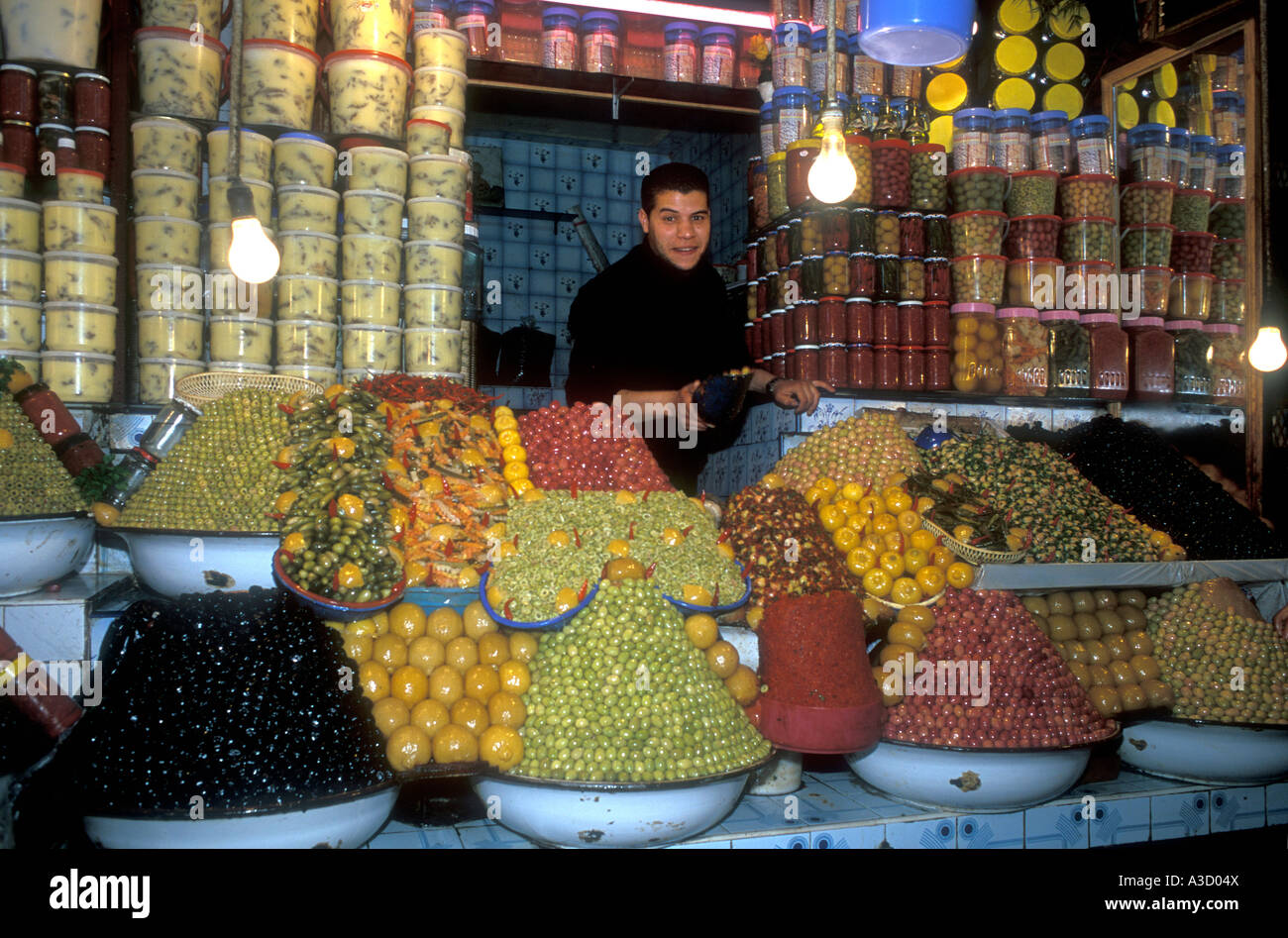Apuesto joven vendiendo aceitunas y conservas de frutas en el zoco en Fez Marruecos Foto de stock