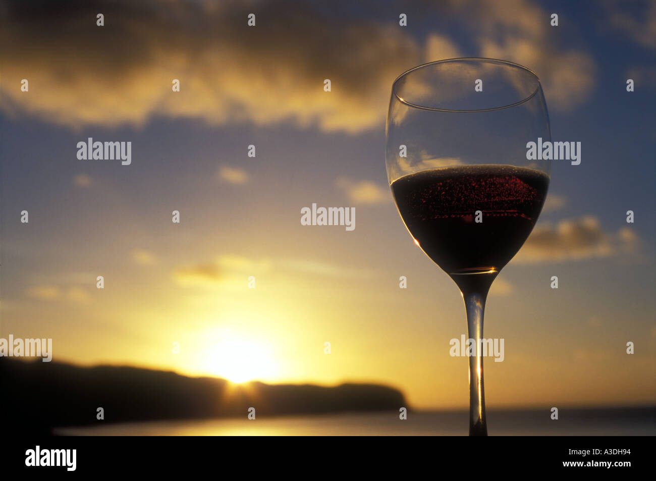 Copa de vino tinto contra una puesta de sol en Nueva Zelanda Foto de stock