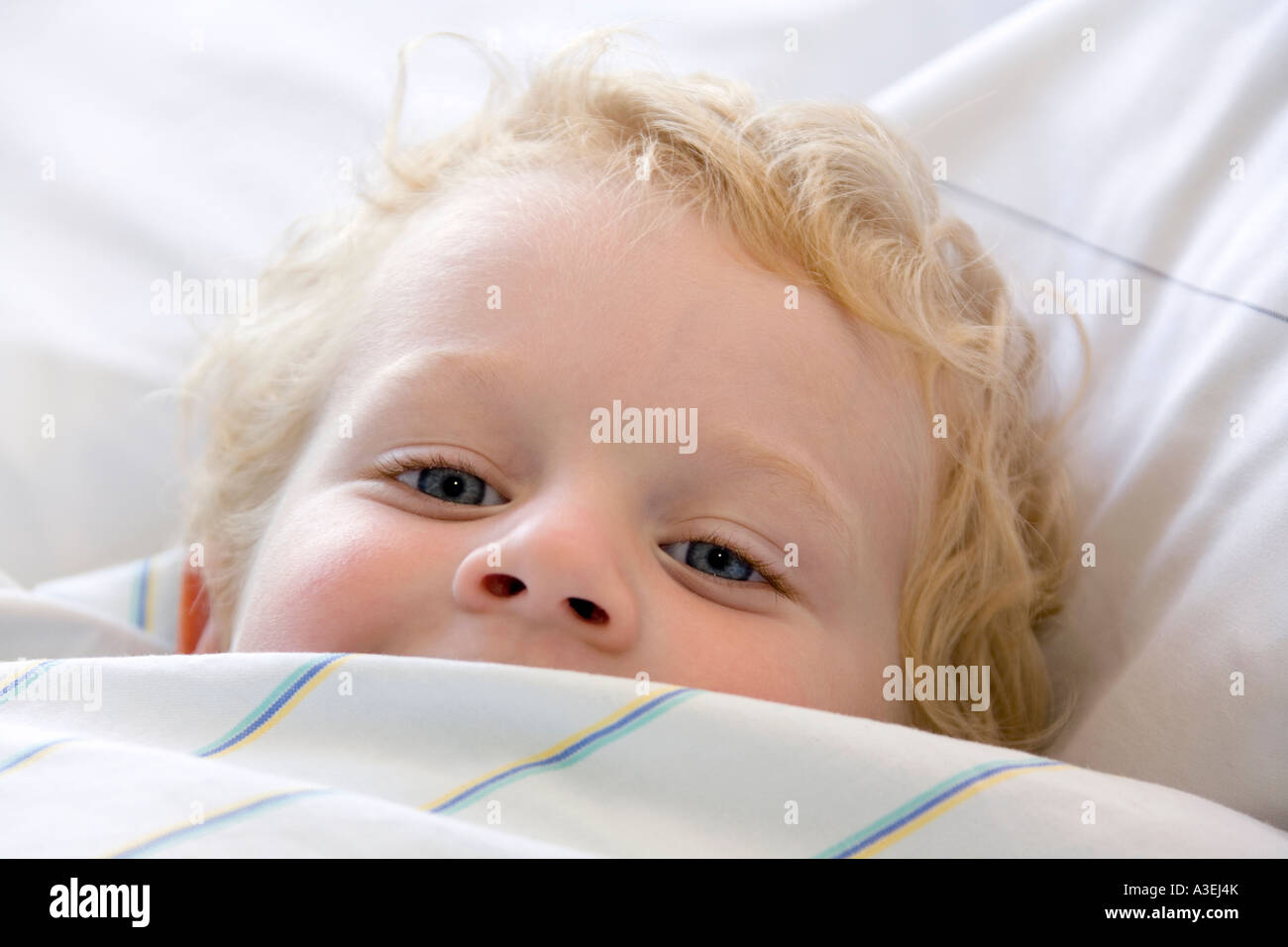 Un niño de dos años de edad snuggles en su cama Foto de stock