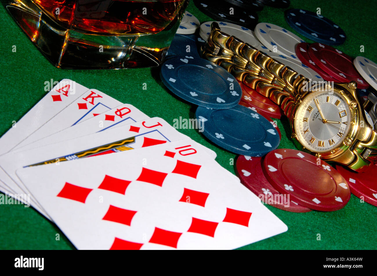Las cartas de póquer mostrando un royal flush con fichas de casino un reloj tirado en un vaso de whisky en las rocas, todo en un tapete verde ca Fotografía de