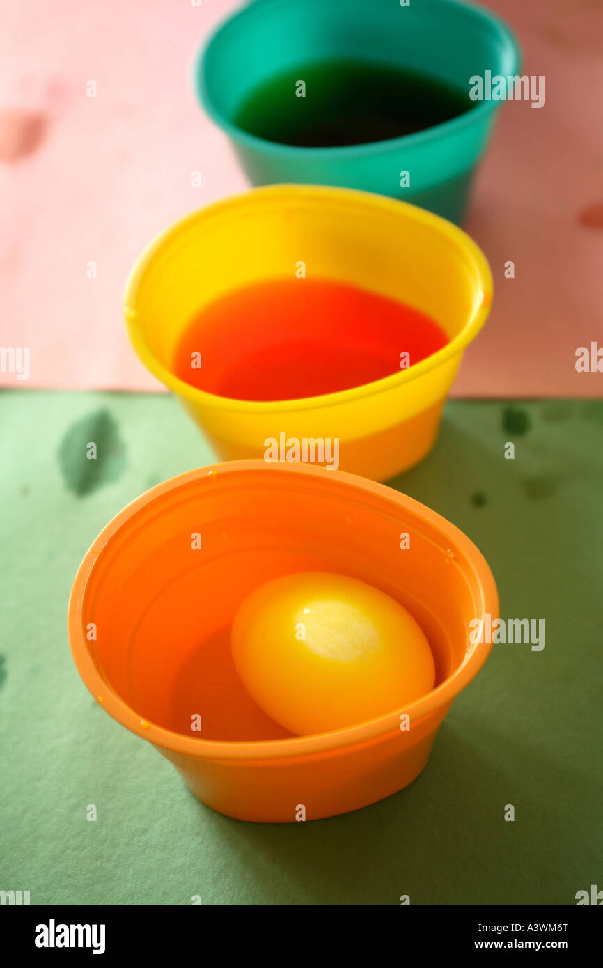 Foto de huevos de Pascua está teñida en varias tazas de tintes de colores brillantes Foto de stock
