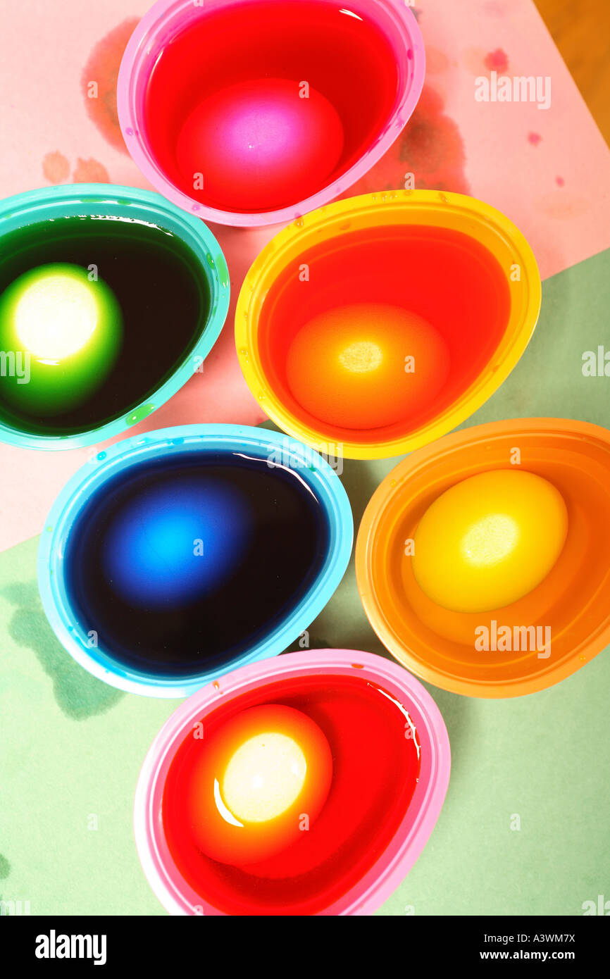 Foto de huevos de Pascua está teñida en varias tazas de tintes de colores brillantes Foto de stock