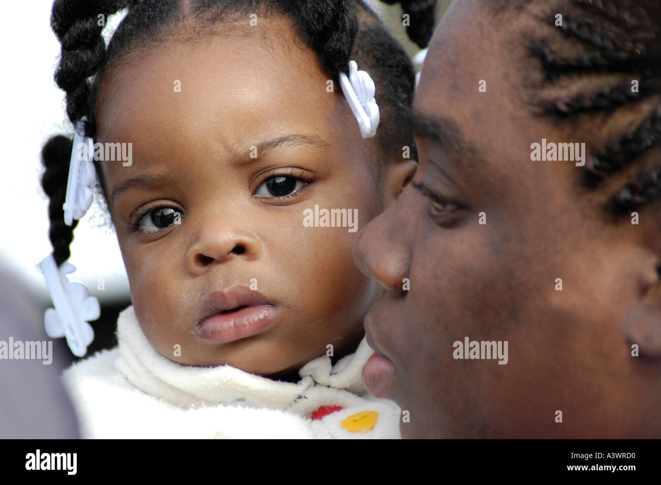 Afroamericano Negro niño bebé, niña con su madre en un evento familiar... bonito rostro con pelo en trenzas Foto de stock