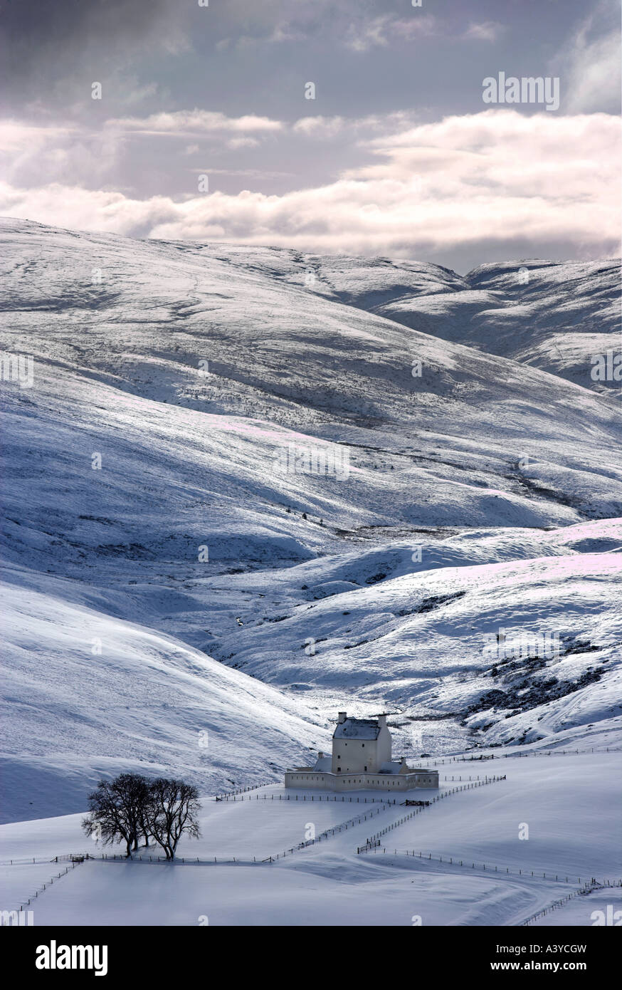 Imagen de formato vertical de Corgarff Castle, Escocia en invierno con nieve y moody cielo brillando en la dramática mountainscape Foto de stock